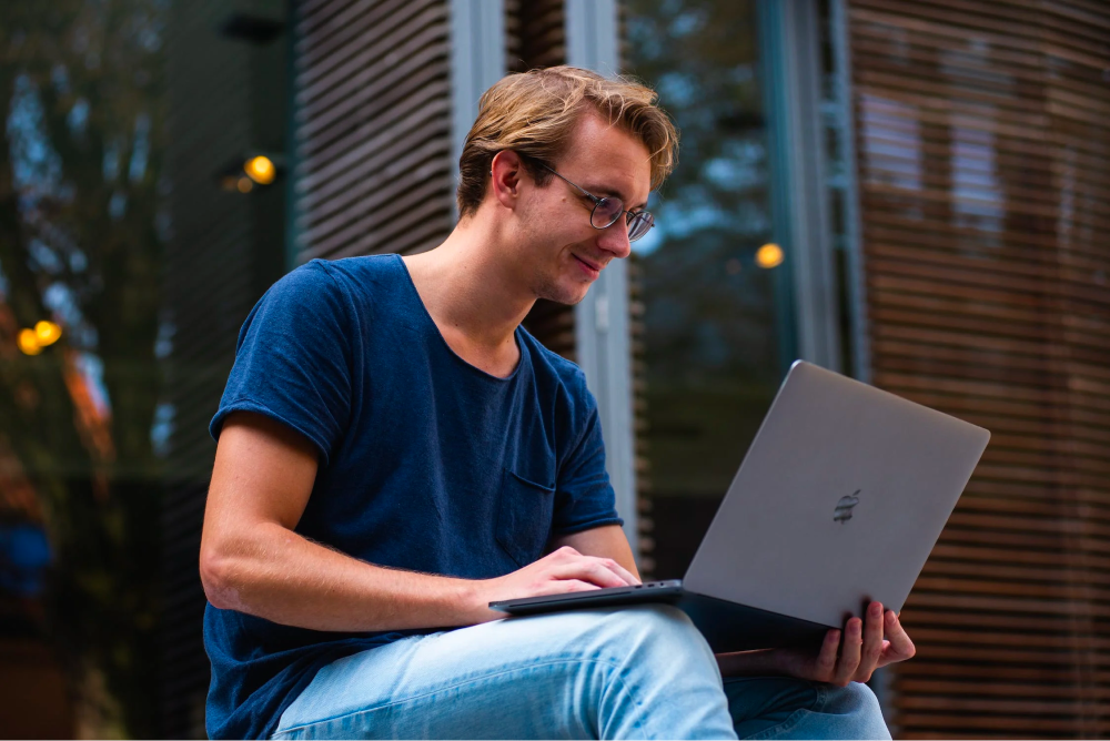 Man sitting on a step with a laptop