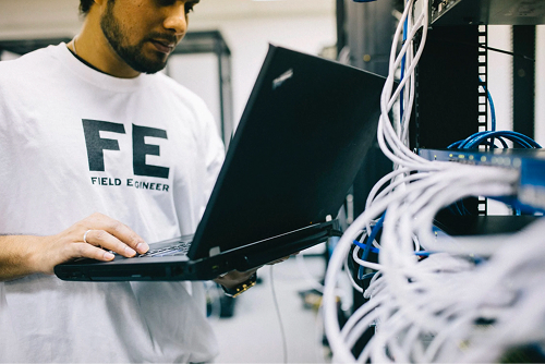 Engineer holding a laptop next to a rack